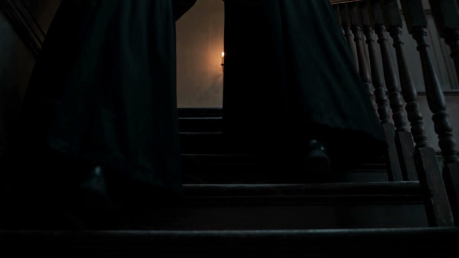 Montée de l'escalier dans le noir, une bougie pour seule source de lumière