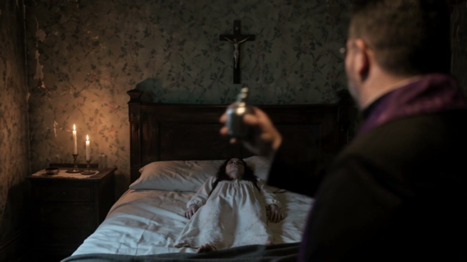 Première aspersion d'eau bénite, la jeune femme allongée sous le crucifix