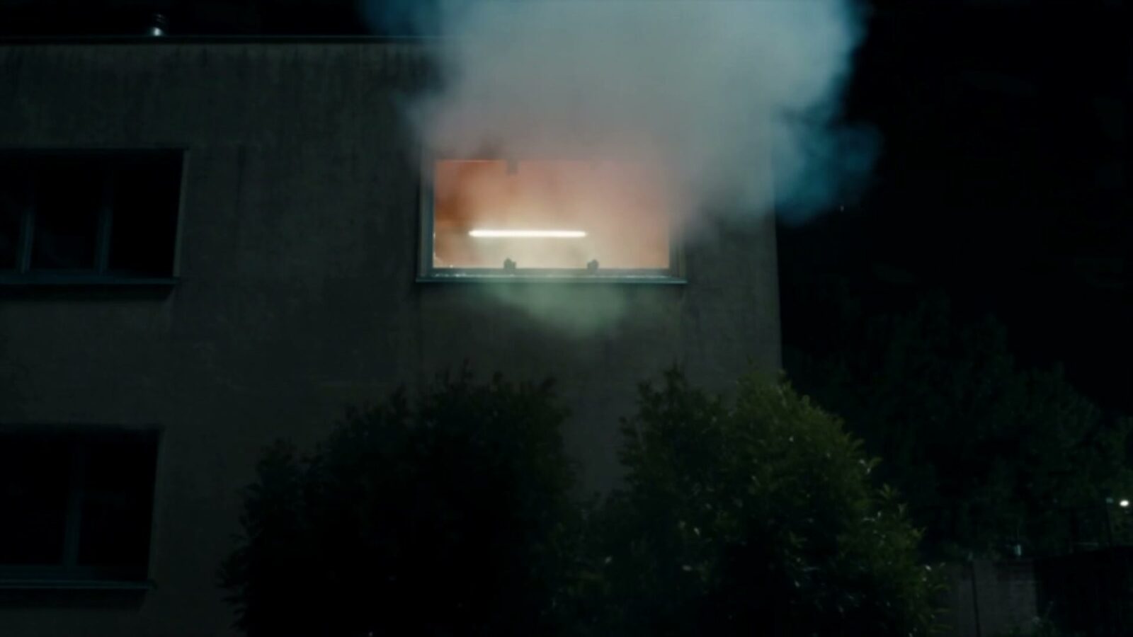 La nuit, une fenêtre éclairée crache une épaisse fumée après l'explosion