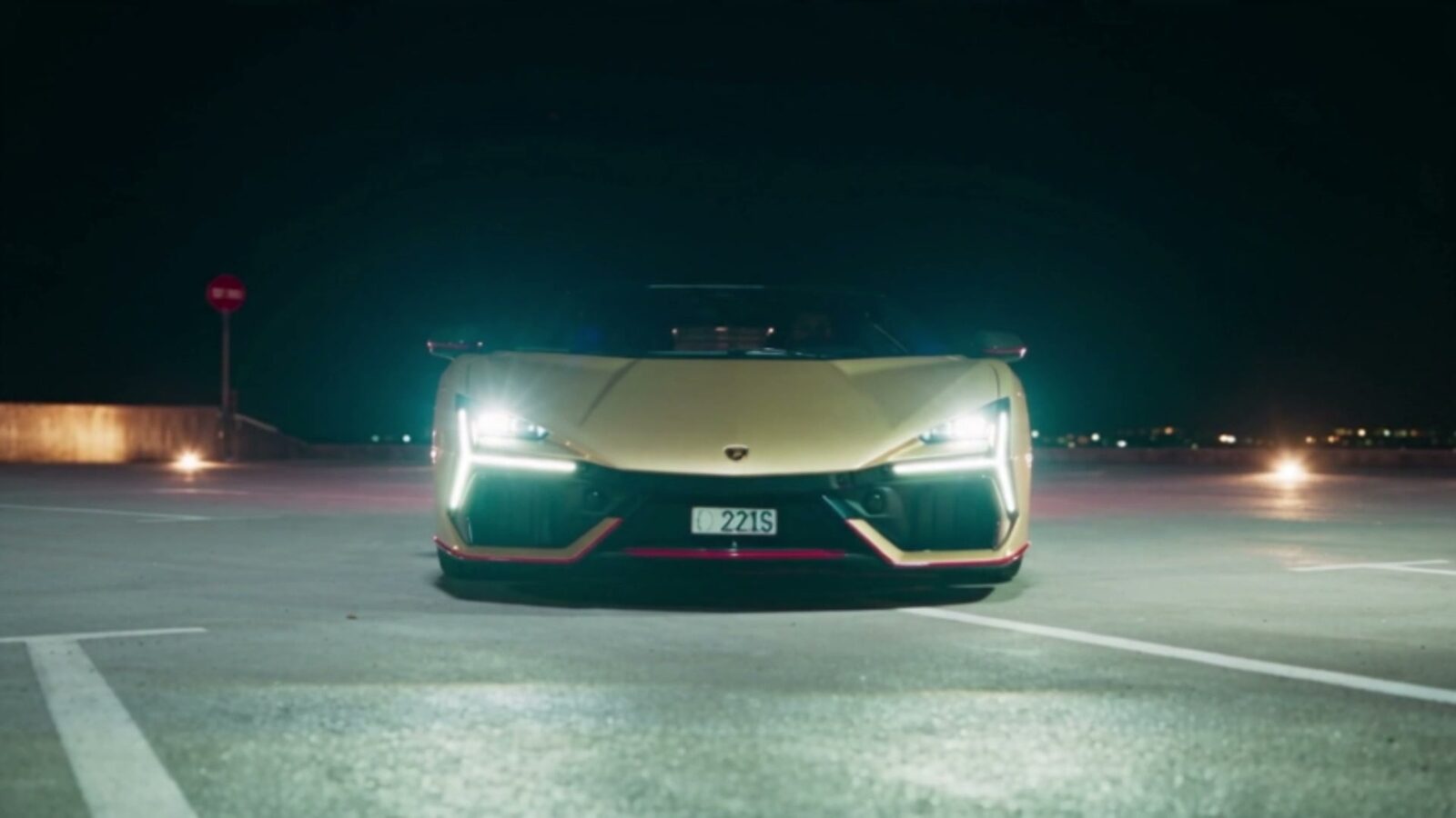 La Lamborghini dorée de face, phares allumés, à l'arrêt sur un quai désert