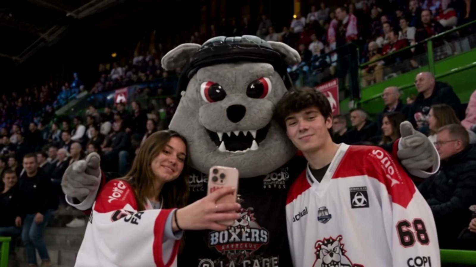 Deux supporters posent en selfie avec la mascotte du club dans les tribunes