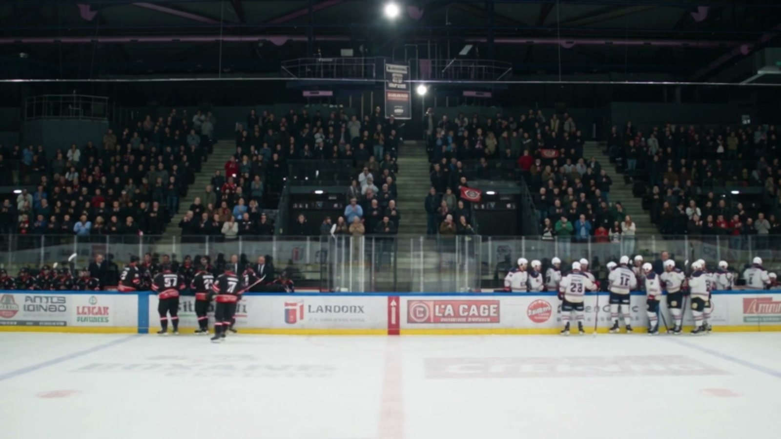 Plan large de la patinoire, les deux bancs debout face aux tribunes pleines