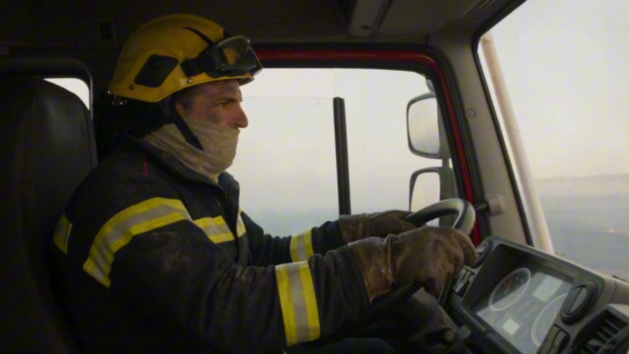 Un pompier masqué au volant de son camion, en route vers le front