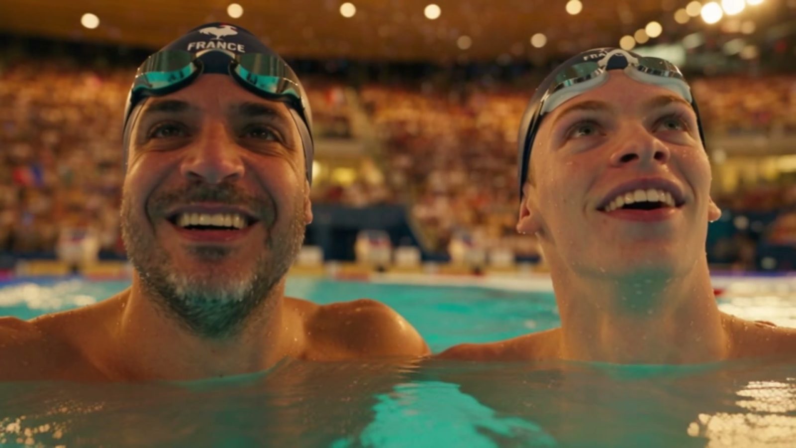 Les deux Français dans l'eau côte à côte, les yeux levés vers le tableau d'affichage