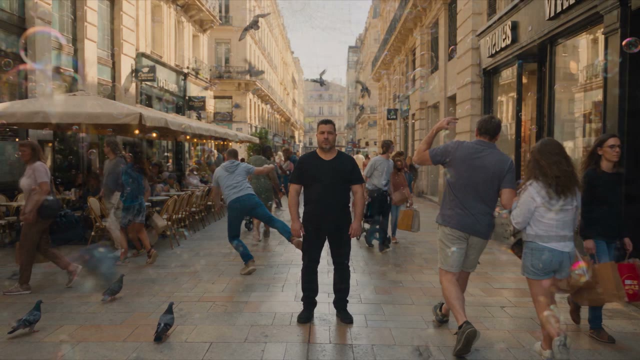 Une rue commerçante entièrement suspendue : des dizaines de figurants immobiles autour d'un seul homme qui marche