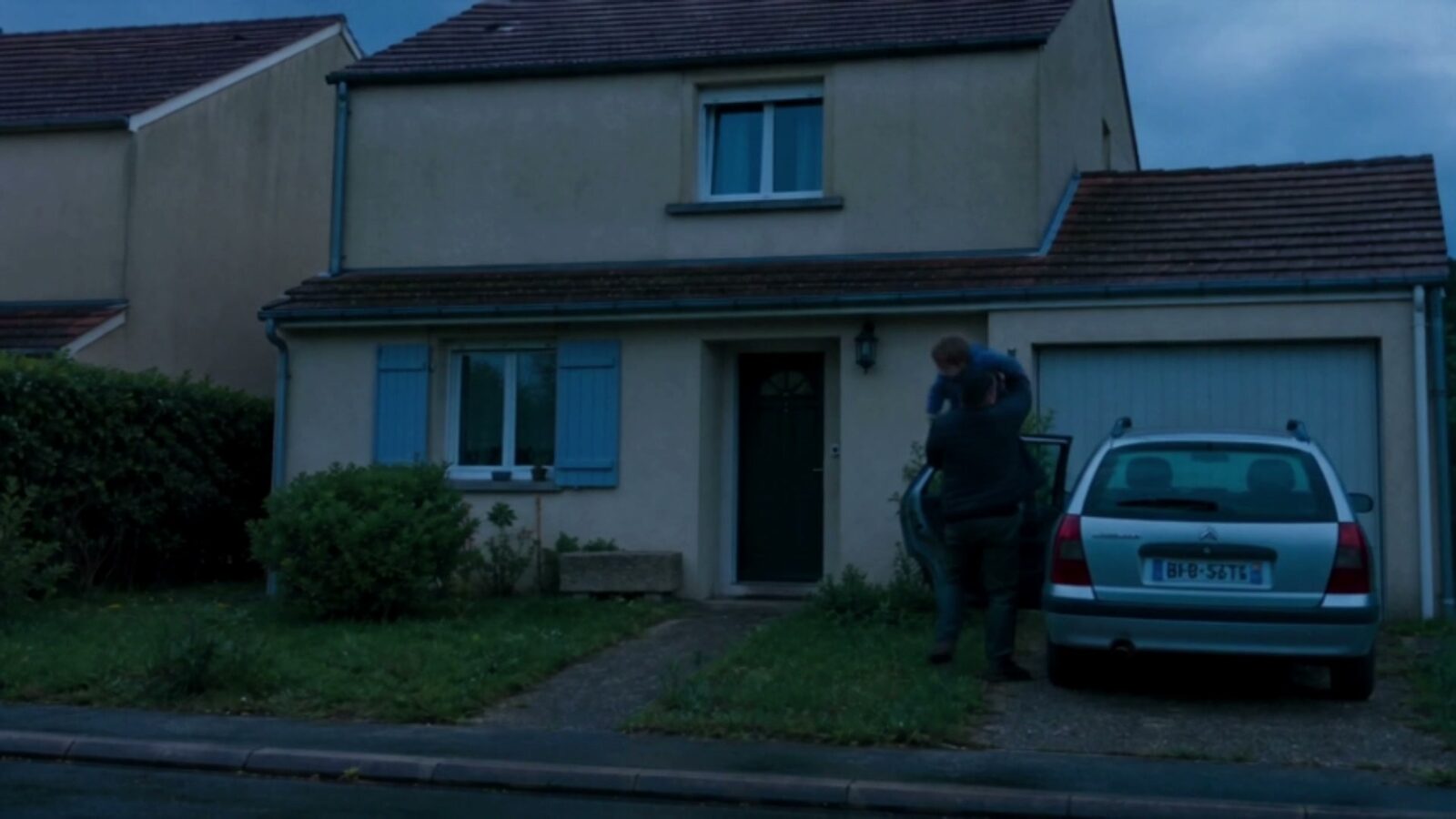 Le soir, devant leur maison, le père sort son fils de la voiture