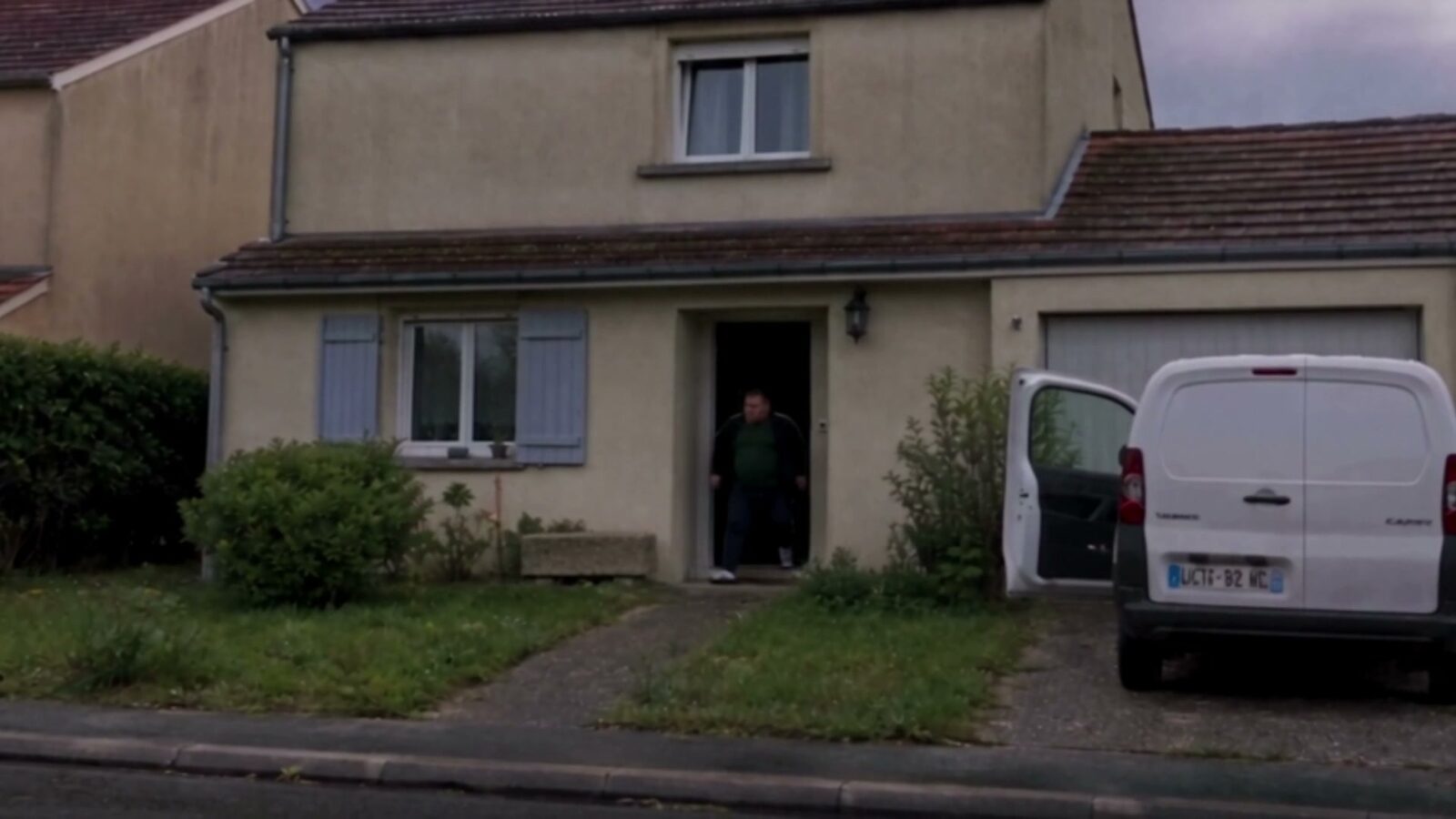 La maison en plein jour, une camionnette blanche garée devant et un inconnu sur le seuil
