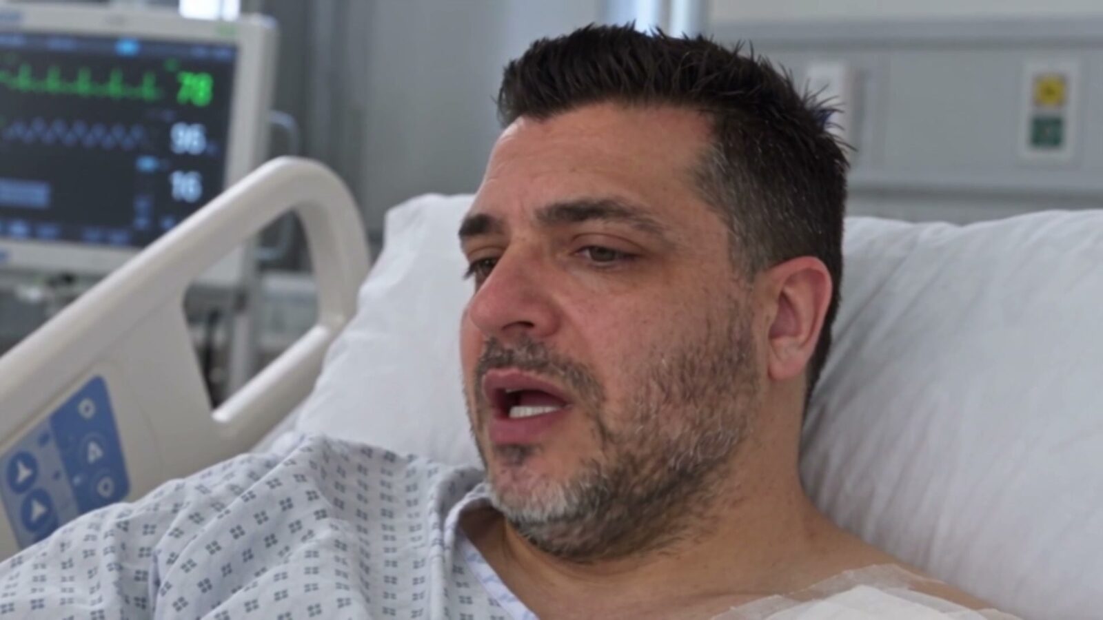 Le père dans un lit d'hôpital, en blouse, à côté d'un moniteur