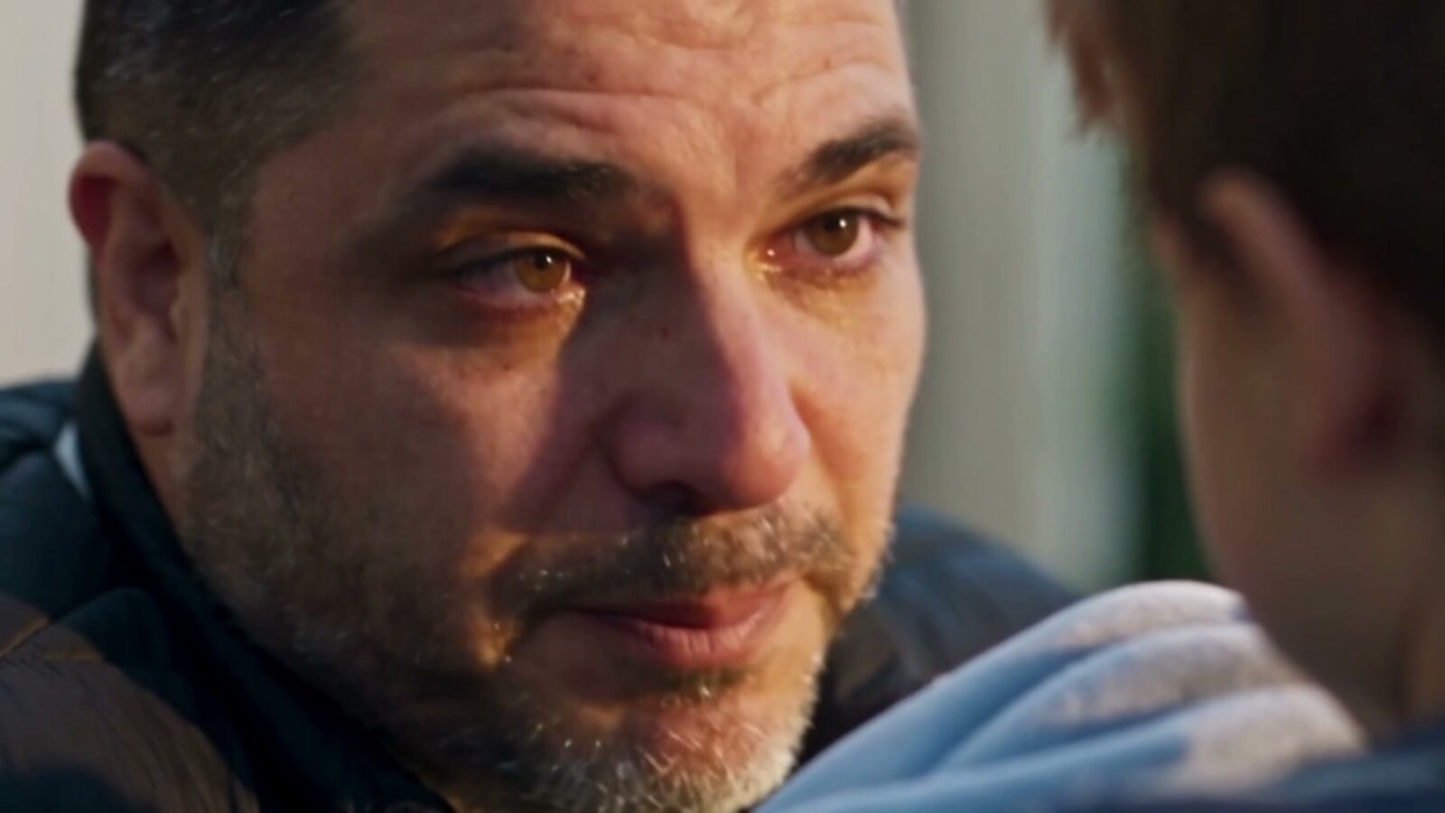 Les yeux pleins de larmes, le père regarde son fils