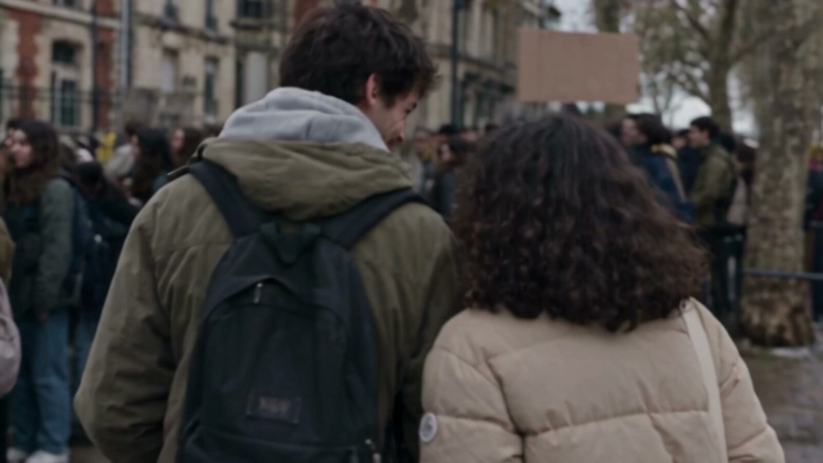 De dos, deux manifestants avancent dans le cortège, sac sur l'épaule
