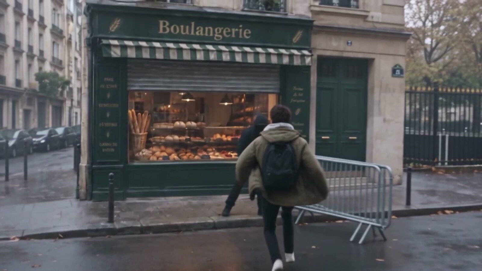 Un manifestant capuche relevée court vers la vitrine d'une boulangerie