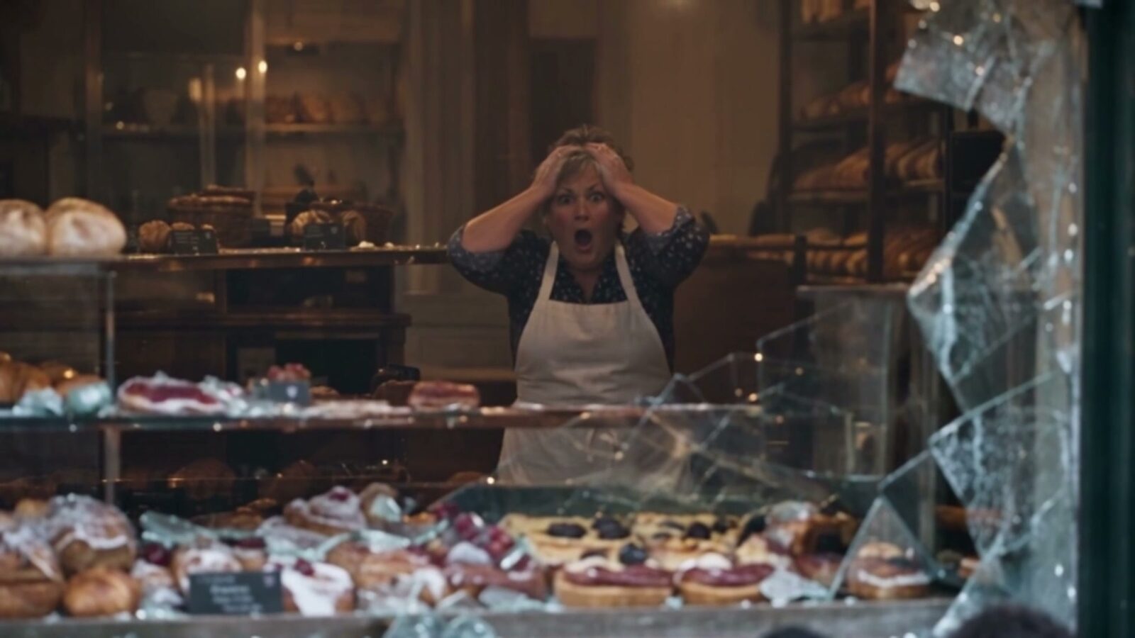 Dans sa boutique, la boulangère se prend la tête entre les mains devant sa vitrine brisée